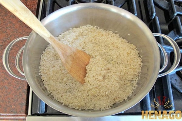 Cho gạo vào nồi và xào thêm một phút nữa